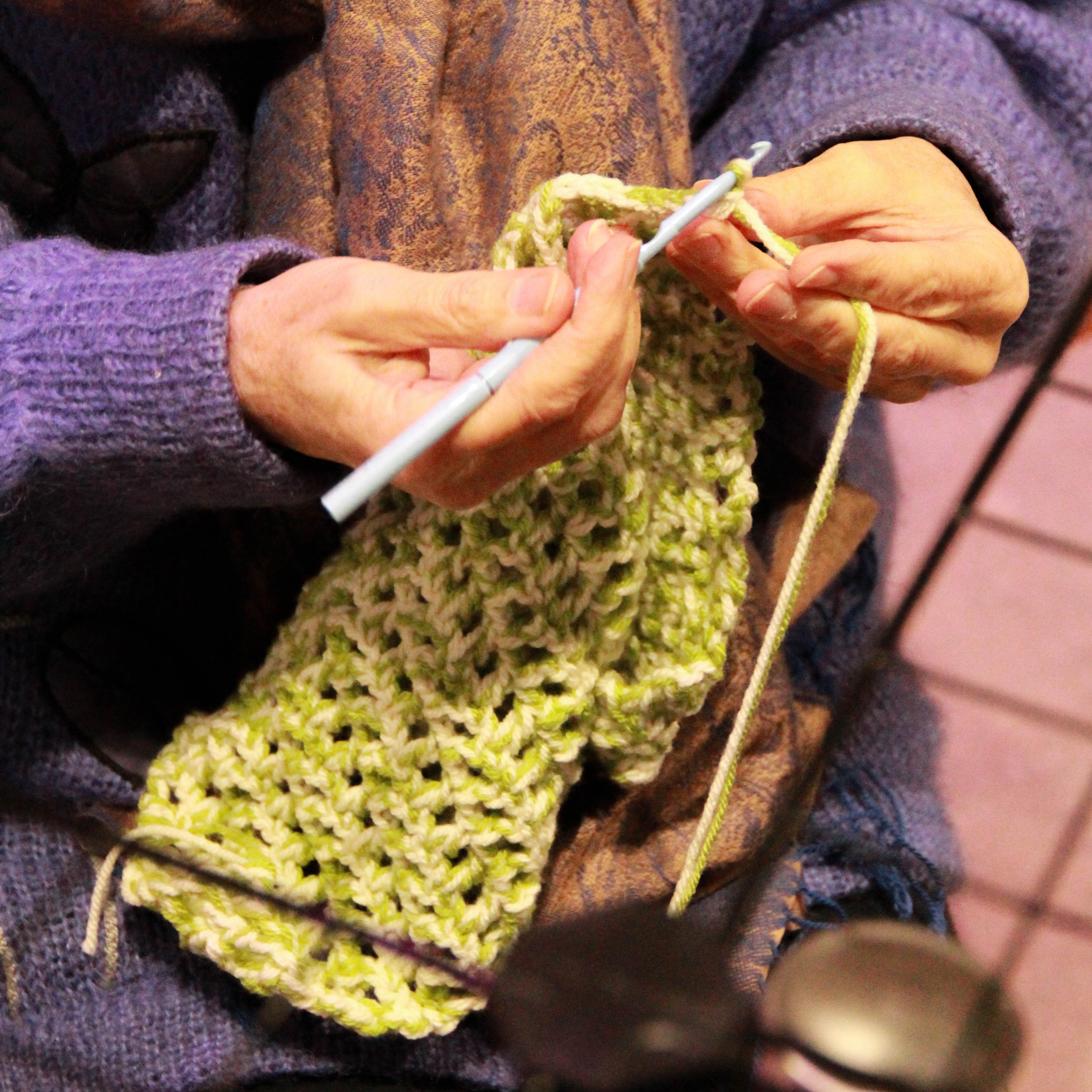 Hands knitting green yarn.